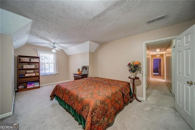 bedroom with a textured ceiling, ceiling fan, lofted ceiling, and light carpet