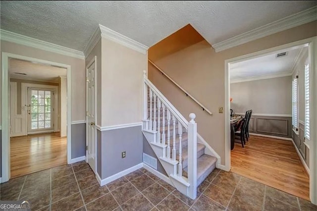 stairway featuring hardwood / wood-style floors, ornamental molding, and a textured ceiling