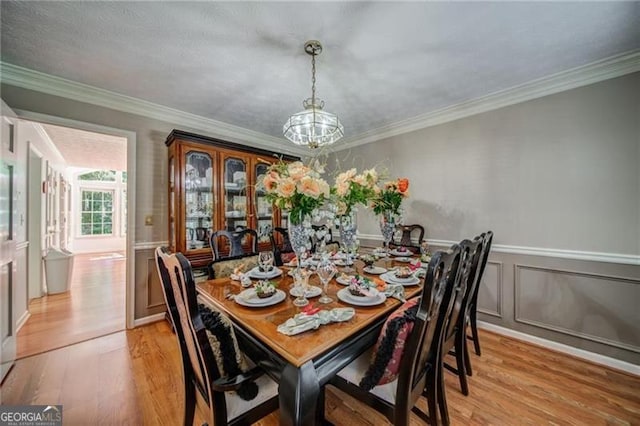 dining room featuring a notable chandelier, light wood-type flooring, and ornamental molding