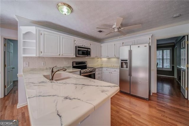 kitchen with white cabinets, kitchen peninsula, and appliances with stainless steel finishes