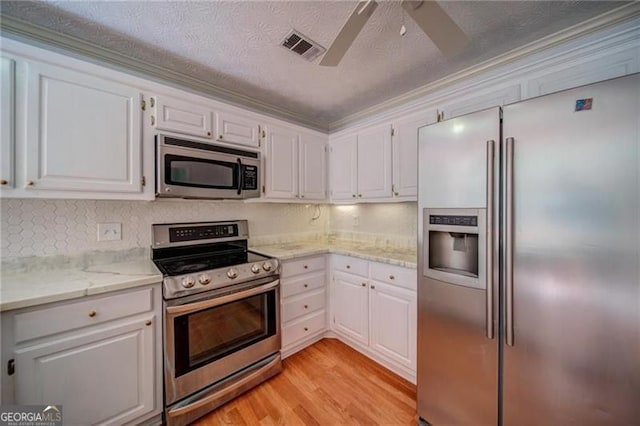 kitchen featuring white cabinetry, stainless steel appliances, light wood-type flooring, and ornamental molding