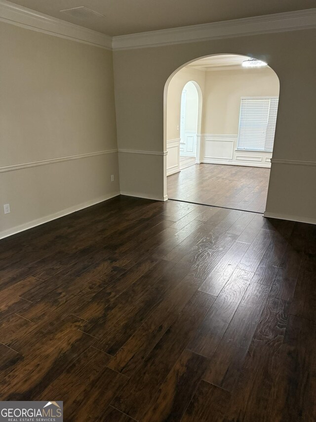 empty room with dark hardwood / wood-style flooring and crown molding