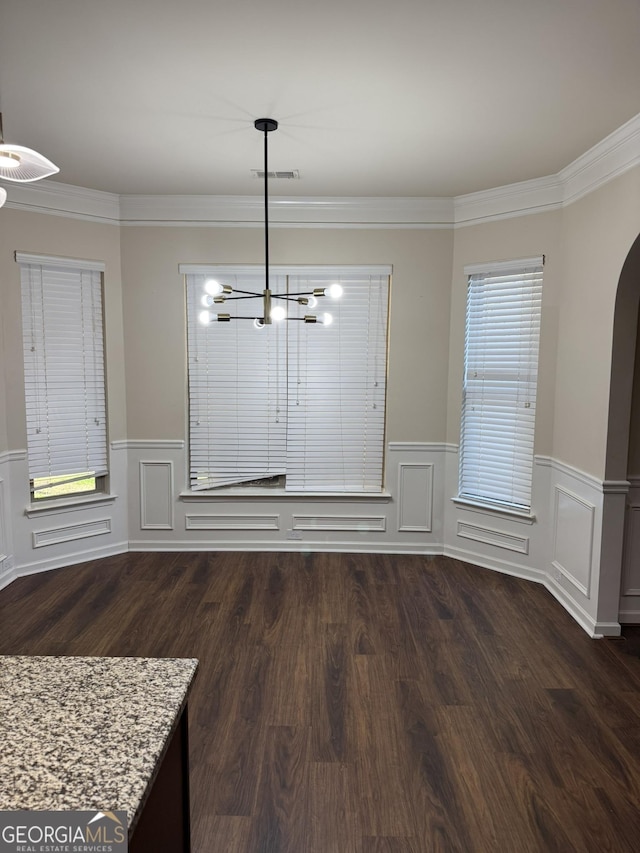 unfurnished dining area featuring dark hardwood / wood-style flooring, a notable chandelier, and ornamental molding