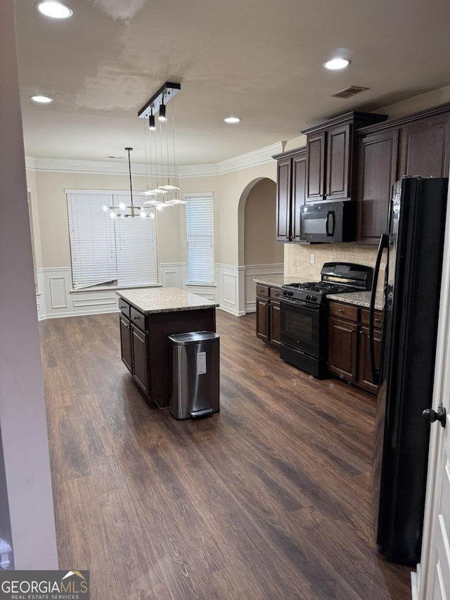 kitchen featuring black appliances, a center island, pendant lighting, and dark brown cabinets