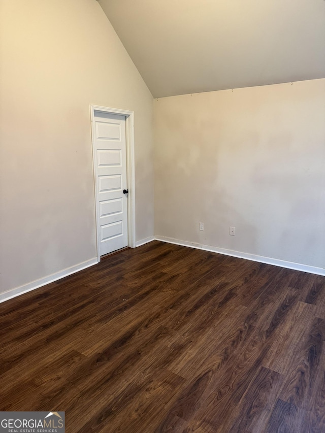 spare room with dark hardwood / wood-style floors and vaulted ceiling