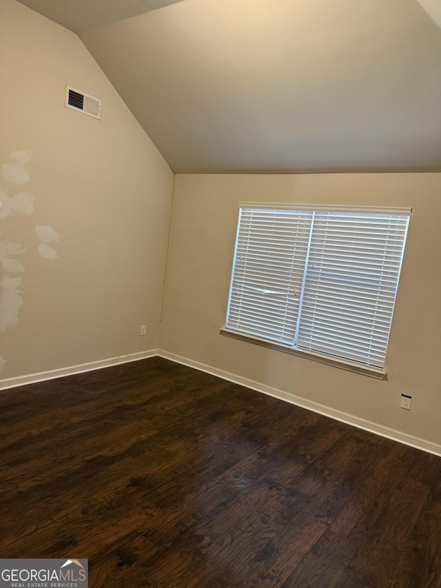 empty room featuring dark wood-type flooring and lofted ceiling