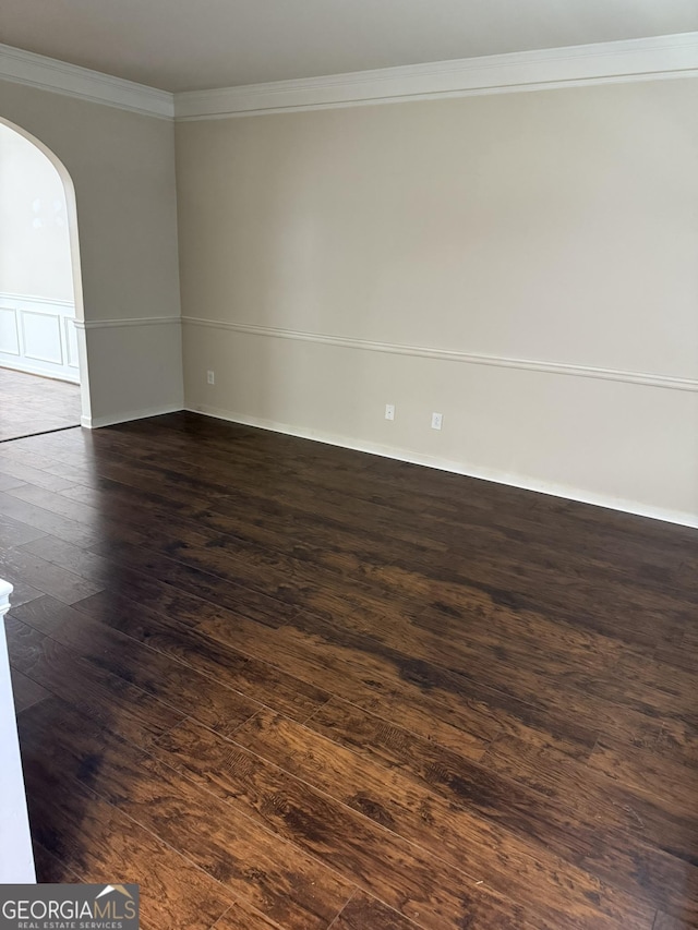 spare room featuring crown molding and dark wood-type flooring