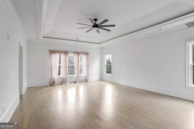 empty room featuring crown molding, ceiling fan, a raised ceiling, and light hardwood / wood-style floors