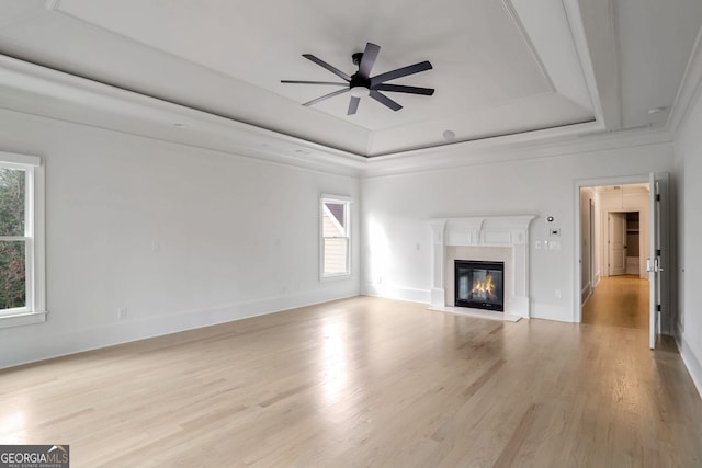 unfurnished living room featuring light hardwood / wood-style flooring, a raised ceiling, and ceiling fan