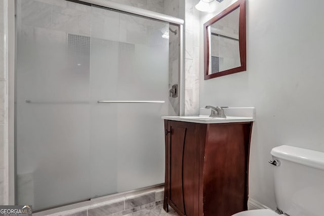 bathroom featuring vanity, toilet, and a shower with shower door