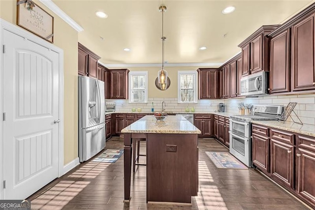 kitchen featuring tasteful backsplash, a kitchen island, appliances with stainless steel finishes, and dark wood-style flooring