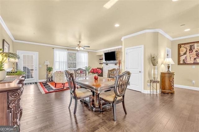 dining room featuring dark hardwood / wood-style floors, ceiling fan, crown molding, and a fireplace