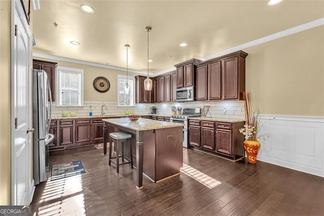 kitchen featuring dark wood-style floors, stainless steel appliances, a kitchen bar, and a kitchen island