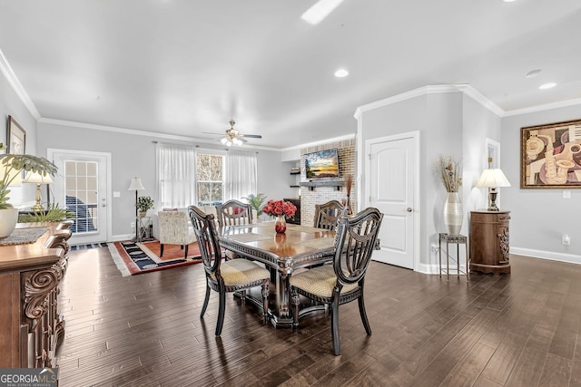 dining space featuring dark wood-type flooring, a fireplace, ornamental molding, and baseboards