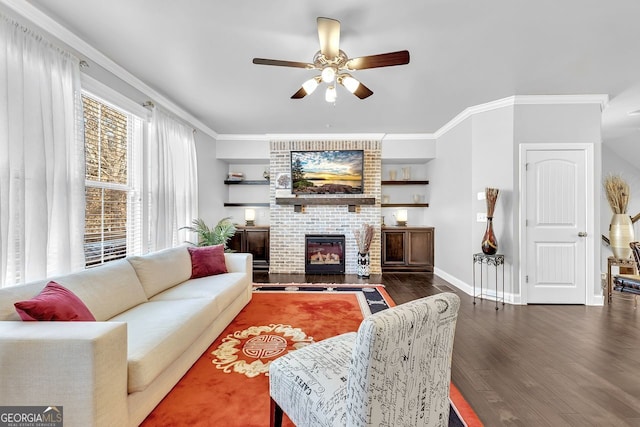 living area featuring ceiling fan, a fireplace, wood finished floors, baseboards, and crown molding