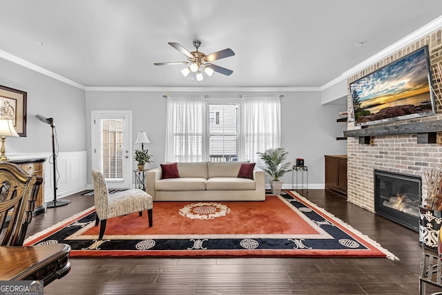 living room featuring ceiling fan, a fireplace, ornamental molding, and wood finished floors