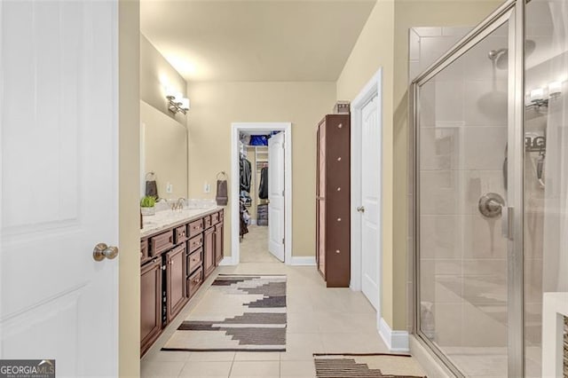 full bath with baseboards, tile patterned floors, a spacious closet, vanity, and a shower stall