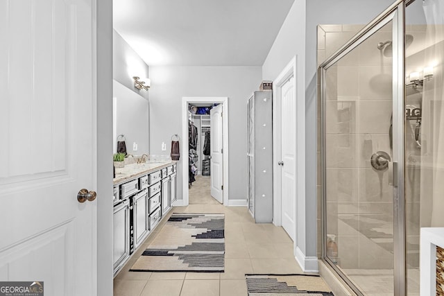 bathroom with a shower stall, vanity, a walk in closet, and tile patterned floors