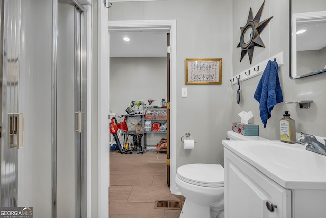 bathroom with tile patterned floors, a shower with door, vanity, and toilet