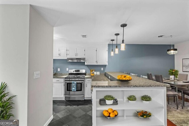 kitchen featuring white cabinets, light stone countertops, stainless steel gas range oven, and hanging light fixtures