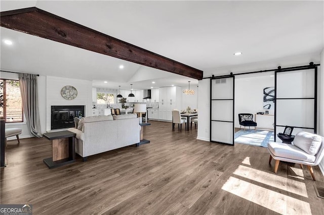 living room featuring a barn door, a large fireplace, a wealth of natural light, and dark wood-type flooring