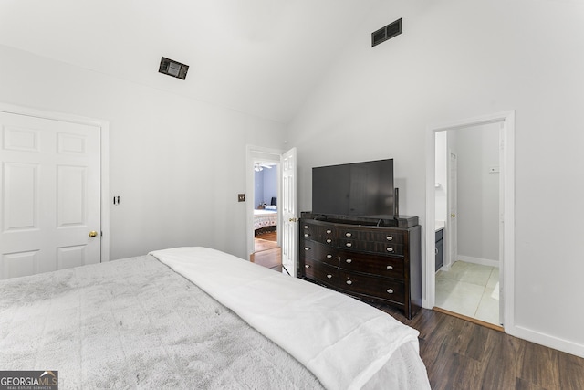 bedroom featuring ensuite bathroom, high vaulted ceiling, and dark wood-type flooring