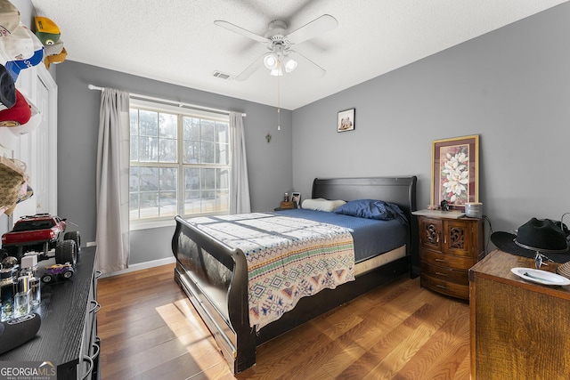 bedroom featuring wood-type flooring, a textured ceiling, and ceiling fan