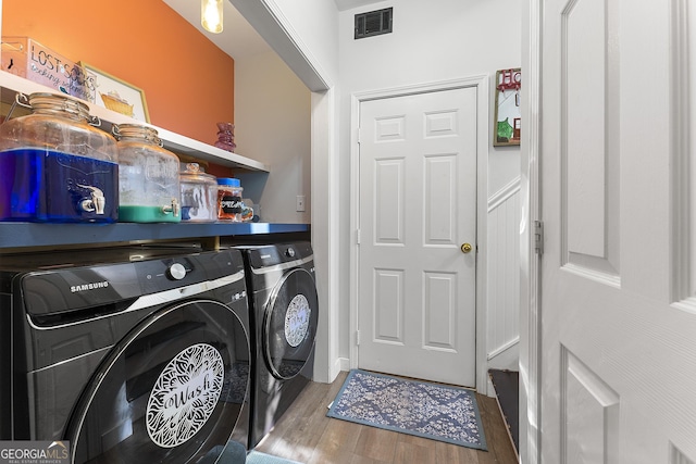 laundry room with washing machine and clothes dryer and hardwood / wood-style floors