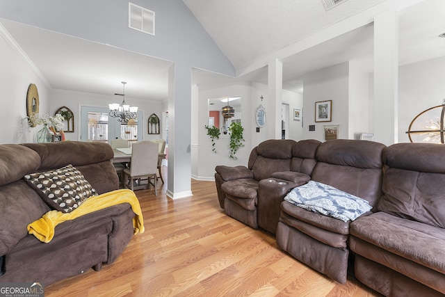 living room featuring light hardwood / wood-style floors, high vaulted ceiling, a notable chandelier, and crown molding