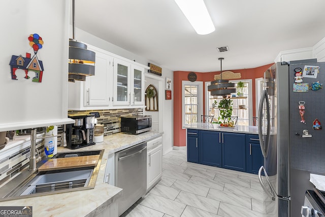 kitchen with tasteful backsplash, stainless steel appliances, blue cabinetry, white cabinetry, and hanging light fixtures