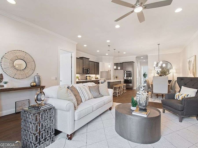 living room featuring ceiling fan with notable chandelier, light hardwood / wood-style flooring, and ornamental molding