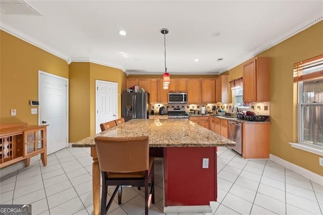 kitchen with appliances with stainless steel finishes, a breakfast bar, crown molding, pendant lighting, and a center island