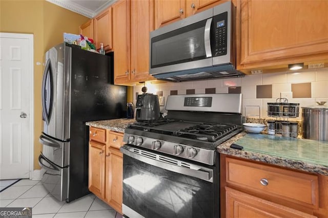 kitchen with stone countertops, light tile patterned floors, stainless steel appliances, and tasteful backsplash