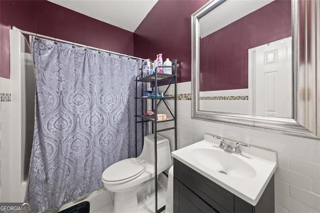 full bathroom featuring shower / bath combo, tile patterned floors, toilet, vanity, and tile walls