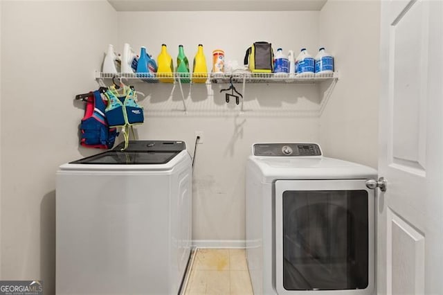 clothes washing area with light tile patterned flooring and washer and dryer