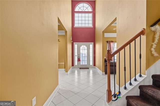 tiled foyer entrance with a high ceiling and crown molding