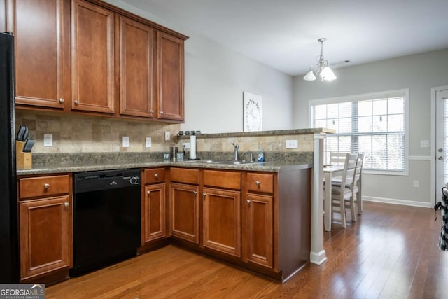 kitchen with light stone countertops, dishwasher, sink, a notable chandelier, and hardwood / wood-style floors