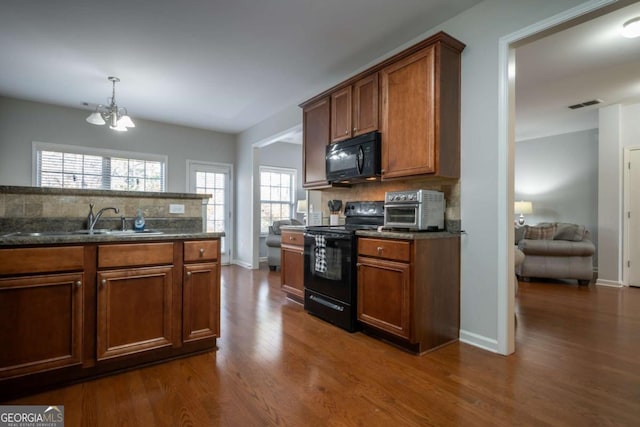 kitchen with sink, tasteful backsplash, dark hardwood / wood-style floors, a notable chandelier, and black appliances