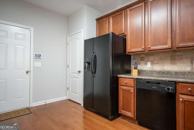 kitchen with backsplash, black appliances, and light wood-type flooring