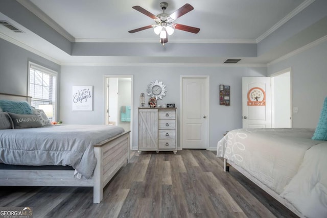 bedroom featuring ceiling fan, dark hardwood / wood-style floors, ensuite bathroom, a tray ceiling, and ornamental molding