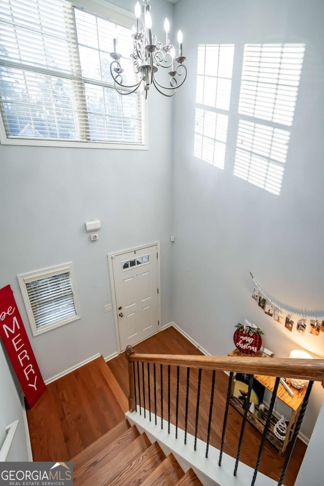 stairway featuring hardwood / wood-style floors and an inviting chandelier