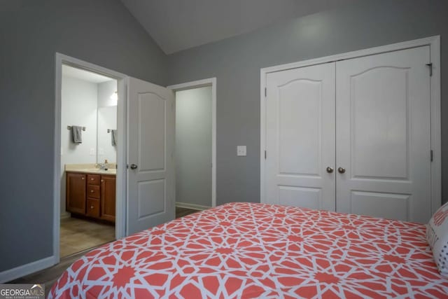 bedroom with connected bathroom, a closet, vaulted ceiling, and sink