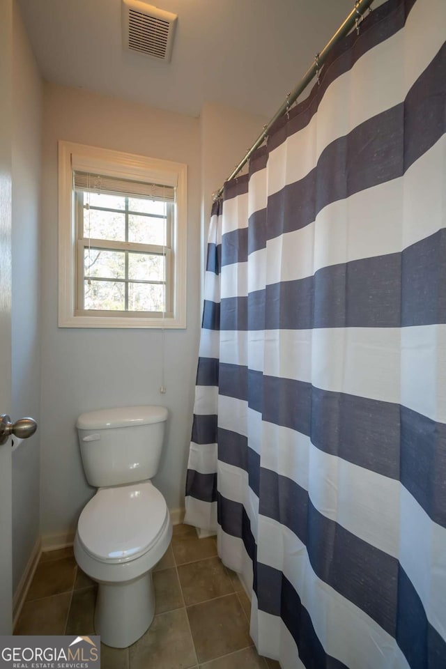 bathroom featuring tile patterned floors, toilet, and walk in shower