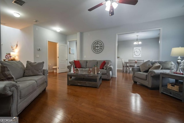 living room featuring dark wood-type flooring and ceiling fan with notable chandelier