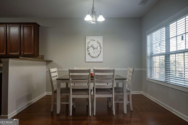 dining area with dark hardwood / wood-style floors and an inviting chandelier