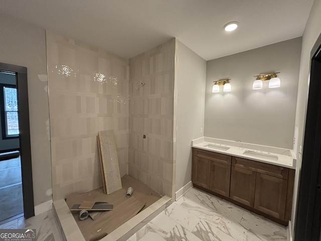 full bathroom with marble finish floor, a tile shower, and baseboards