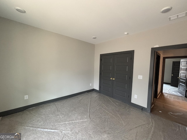 unfurnished bedroom with a closet, carpet, visible vents, and baseboards