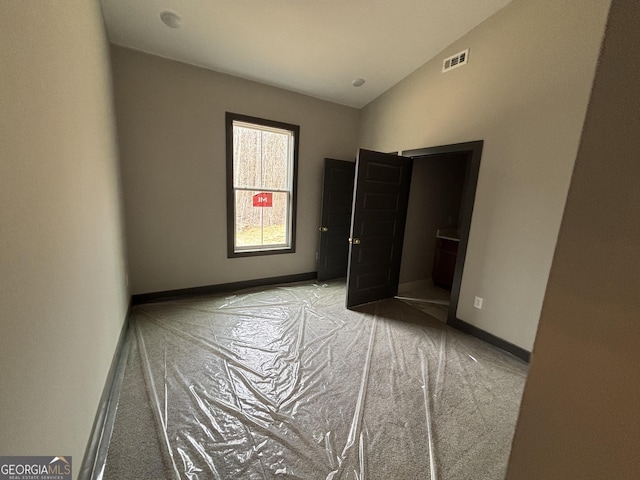 unfurnished bedroom featuring lofted ceiling, visible vents, light carpet, and baseboards