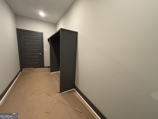 hallway with concrete floors and baseboards