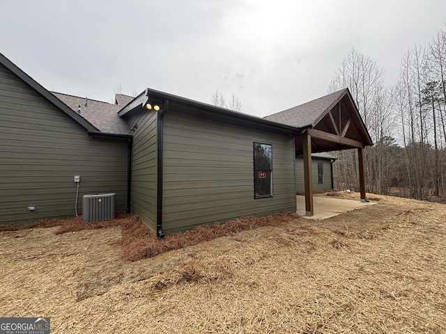 view of property exterior with roof with shingles, a patio, and central AC unit